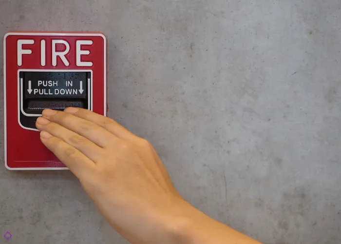 Technician installing fire alarm safety system devices on building wall