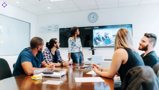 Professional meeting room with video conferencing system, microphones, and digital screen setup.